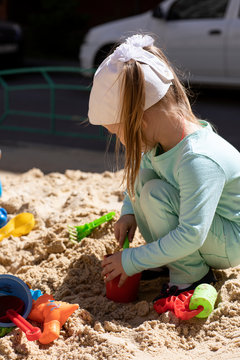 A little, pretty, active girl plays on the playground on a sunny day.