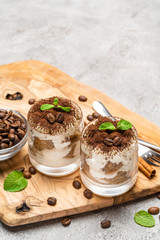 Classic tiramisu dessert in a glass on dark concrete background