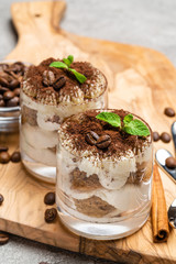 Classic tiramisu dessert in a glass on dark concrete background