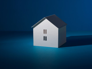 White house on a blue background. Symbol of a separate residential two-story building. Model cut out of paper