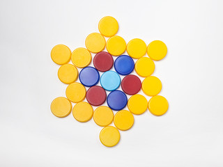 red, blue, yellow, plastic bottle caps are lined up in the shape of a star on a white background.