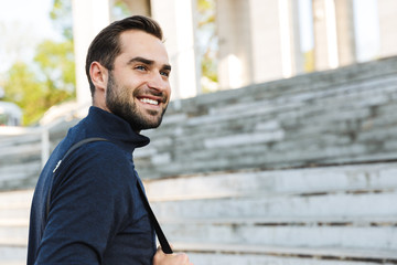 Naklejka premium Handsome young strong sports happy man posing outdoors at the nature park location.