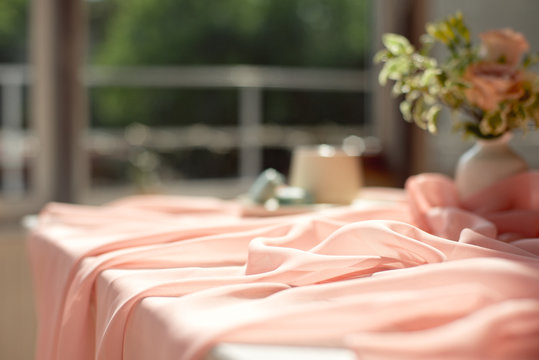 Pink transparent tablecloth on a wooden white table a cup of coffee or tea with french macaroons