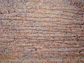 Background red natural granite stone. Black and light blotches. Parallel grooves and scratches. Texture. Matte coating.