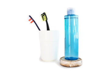 face tonic and toothbrushes in white glass