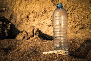 water flows out of a plastic bottle on the sea sand. water saving. last water drop