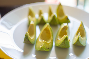 slice of avocado on white dish for healthy fruit. soft focus.