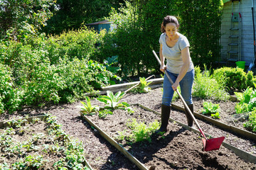 Woman at gardening works with plow in flower beds