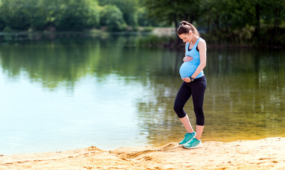 Pregnant woman walking at lakeside, sport during pregnancy