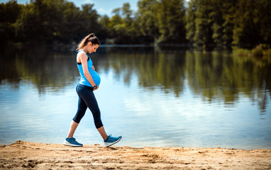 Pregnant woman walking at lakeside, sport during pregnancy