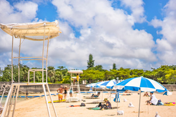 Beach umbrellas and Lifeguard chairs on the sandy beach Naminoue in Naha City in Okinawa Prefecture, Japan.