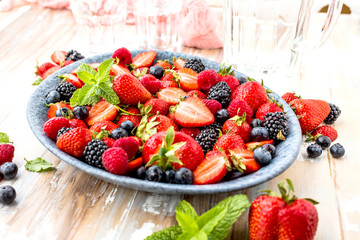 Draufsicht von frischen reifen Erdbeeren, von Blaubeeren und von Brombeeren auf Holztisch mit...