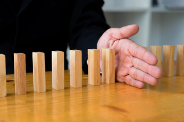 Business hand stops domino continuous overturned meaning that hindered business failure. Stop over...