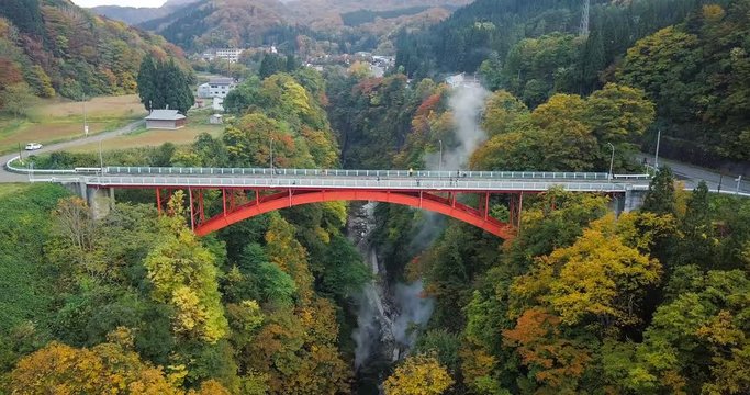 Aerial of Oyasu ravine Oyasukyo onsen and Kawarayu bridge in autumn (fall) leaf colors. Valley of hot springs mineral bath or Bathtub of Hell. Minase, Yuzawa, Akita, Japan