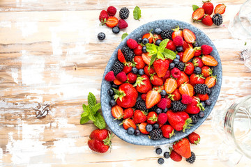 Draufsicht von frischen reifen Erdbeeren, von Blaubeeren und von Brombeeren auf Holztisch mit...