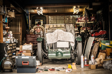Retro vintage auto bedekt met witte doek. Renovatieproject in de garage met veel mechanische details en gereedschappen