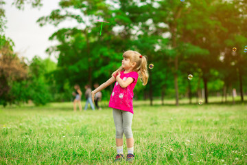 Little girl playing on the meadow on sun with windmill in her hands. Child holding wind toy on wheat field.