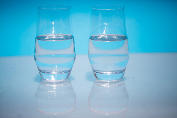 Half-full water glasses, two half-empty water glasses against a blue background