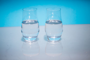 Half-full water glasses, two half-empty water glasses against a blue background
