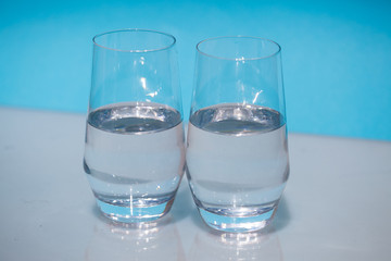 Half-full water glasses, two half-empty water glasses against a blue background