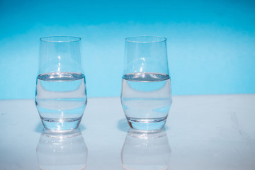Half-full water glasses, two half-empty water glasses against a blue background