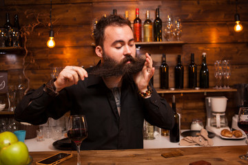 Bearded barman being funny with his beard behind the counter.