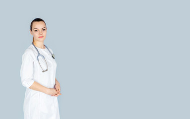 Young female doctor in white uniform with phonendoscope on her neck on blue background with space for text. Healthcare concept