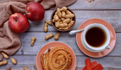 Rustic. Sweet bun. Cup of tea. Peanuts. Red apples. Wood background. Nuts. Fall. Autumnal still life. Top view.