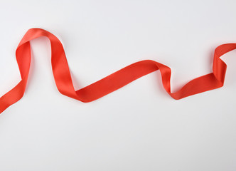curled red satin ribbon on a white background