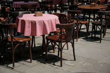 empty wooden chairs and tables in a street cafe