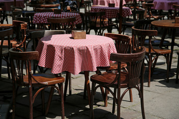empty wooden chairs and tables in a street cafe