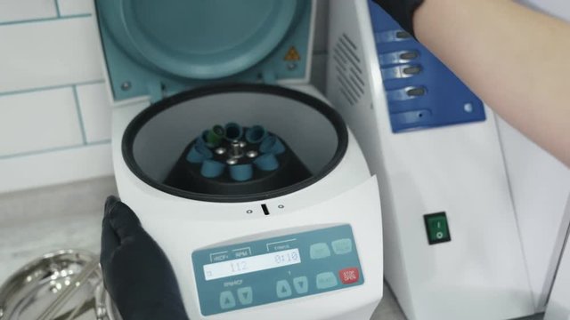 Close up doctor hands open plasma lifting centrifuge, slow motion