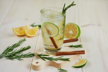  lemonade with fresh lemon, lime, decorated with a rosemary branch on a light wooden background