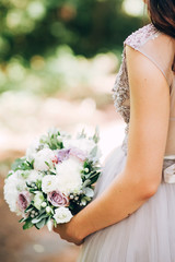 Bride holding a bright wedding bouquet with different flowers