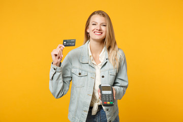 Smiling joyful young woman holding wireless modern bank payment terminal to process and acquire...