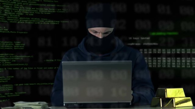 Criminal in balaclava working on laptop, hacking bank security system, data code