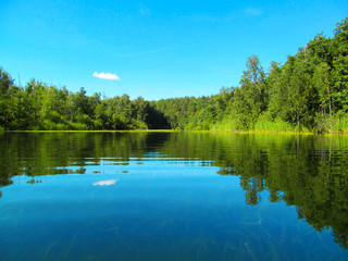 Obraz na płótnie Canvas Summer idyllic landscape with lake and sky. Bright quiet day and calm water surface on silent backwater. Harmony and pacification of nature - a beautiful view for wallpaper.