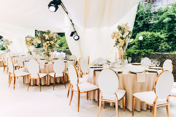 Wedding in a white tent by the lake. Beautiful flowers. luxurious wedding decor in white.