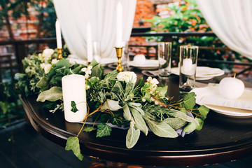 Boho wedding table setting, rustic decorations, gold and blue details, wooden table, bokeh. Luxury wedding decor. Monstera leaves and orchid flowers.