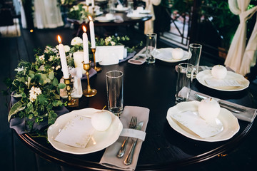 Boho wedding table setting, rustic decorations, gold and blue details, wooden table, bokeh. Luxury wedding decor. Monstera leaves and orchid flowers.
