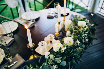 Boho wedding table setting, rustic decorations, gold and blue details, wooden table, bokeh. Luxury wedding decor. Monstera leaves and orchid flowers.
