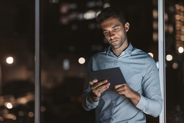 Young businessman using a tablet in his office at night