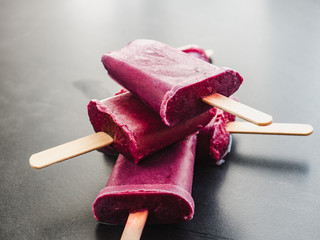 Bright, fruity red ice cream with wooden sticks on a black table. Close-up, top view. Tasty and healthy food concept