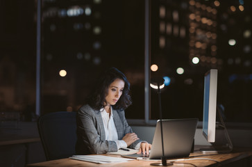 Young businesswoman working online in an office at night
