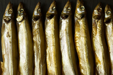 Smoked fish. Little smoked fish,  capelinlies on a slate stone Board. fish background 