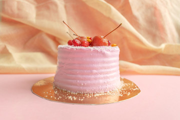 Pink cake on pastel background. Piece of biscuit patterned cake with blue mastic and decor fruits and berries
