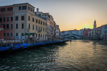 Fototapeta na wymiar Row of gondolas and Rialto bridge in the background at the morning, Venezia, Italy