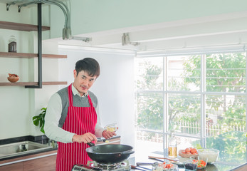 Handsome, Asain young man in Red apron. Cooking for food in the kitchen Room at Home. and people concept, copy space.