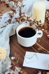 cup of coffee and a sprig of cherry blossoms on a wooden background