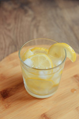 glass of water with lemon on wooden background